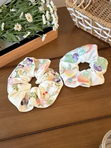 Detail of white satin scrunchies with floral embroidery on a rustic wooden table