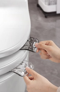 Close-up of a grey toilet seat lifter handle installed on a lid for hygienic lifting