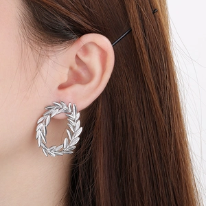 Close-up of a silver olive leaf wreath hoop earring worn by a model for size and scale