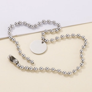 Gros plan d'un collier à billes argenté avec un pendentif rond poli sur une surface plane