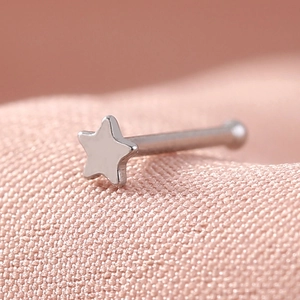 Macro detail of a silver star-shaped stainless steel nose stud with straight bar design