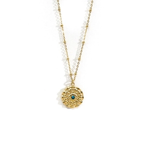 Detail of 14K gold plated necklace with blue gemstone and wavy textured pendant