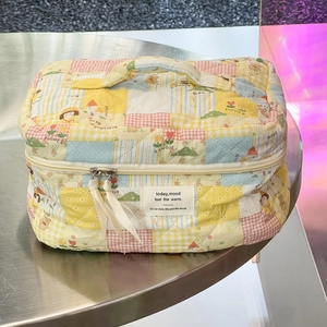 Detail der gesteppten Kosmetiktasche mit pastellfarbenem Blumenmuster und Seidenband