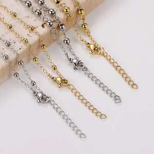 Detailed macro view of 18k gold and silver beaded link chains with lobster clasps