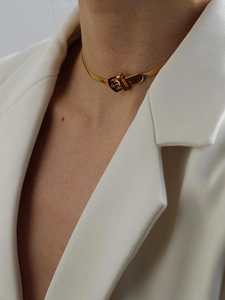 Dettaglio di collana a catena serpente dorata con fibbia moderna indossata da modella