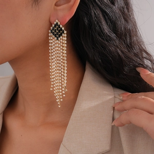 Detail of luxury rhinestone tassel earrings on model showing diamond fringe and gold finish