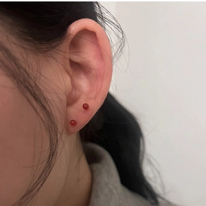 Close-up of minimalist red agate stud earrings worn by a model for a stylish look