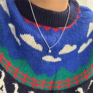 Detail of minimalist 925 sterling silver ball pendant necklace on a knitted sweater