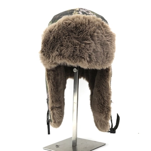 Detail of winter trapper hat featuring camo canvas fabric and thick brown faux fur lining