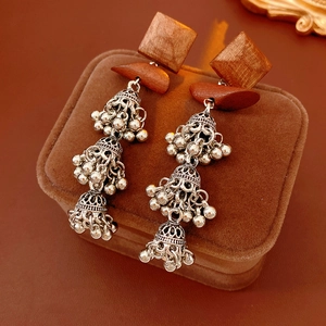Close-up of wooden Jhumka tassel earrings with silver bells on brown velvet case