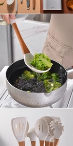 White silicone kitchen utensils with wooden handles used for cooking fresh broccoli