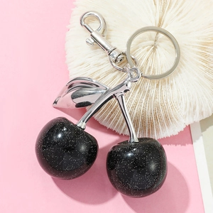 Close-up of glittery black cherry keychain with silver metallic leaves on coral decor