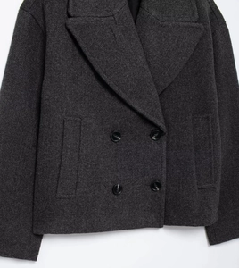 Detail of dark grey wool blend short coat showing double-breasted buttons and fabric texture