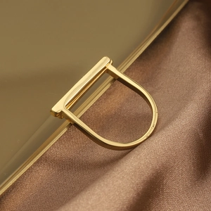 Macro shot of minimalist gold geometric D-shape ring with polished mirror finish