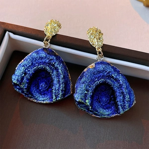 Macro shot of dark blue crystal cluster earrings with hammered gold metal texture