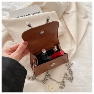 Detailed view of brown mini chain bag interior showing storage space for lipstick
