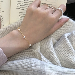 Elegant s925 silver beaded bracelet with white pearls on a model against a warm sweater background