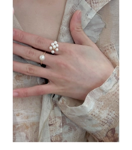 Close-up of golden metal rings featuring a single pearl and a pearl flower design