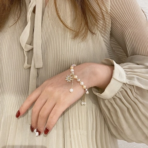 Baroque freshwater pearl bracelet with zircon sunflower pendant on a woman's wrist