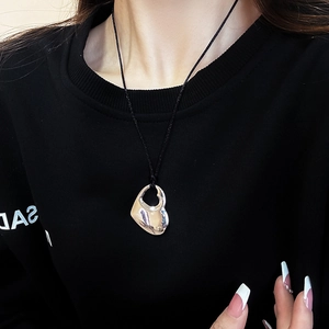 Close-up of polished silver hollow double heart pendant on a black woven cord necklace
