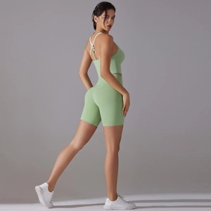 Detail of cross-back mint green yoga bra and high-waist shorts set on female model