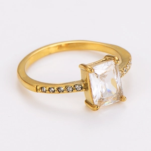 Detail of square zircon ring with gold finish and side accent stones on a white background