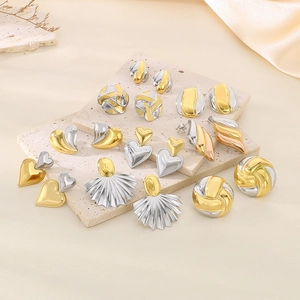 Vue à plat de boucles d'oreilles cœur et géométriques sur une surface en marbre