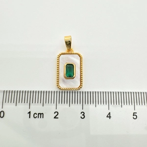 Close-up of a 1.5cm rectangular gold pendant with white shell inlay and green gemstone