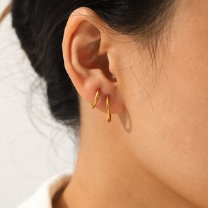 Élégantes boucles d'oreilles créoles en acier inoxydable doré 18 carats portées par un mannequin