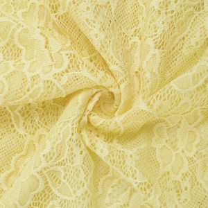 Macro detail of soft light yellow lace fabric with intricate floral patterns and textures