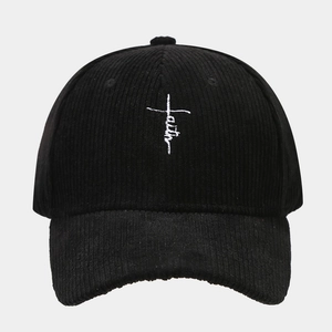 Détail d'une casquette en velours côtelé noir avec broderie blanche en forme de croix