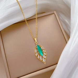 Detailed view of leaf pendant with green oval gemstone and clear crystals on silk