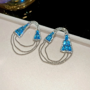 Gros plan de boucles d'oreilles en zircon bleu avec glands à trois couches de chaînes