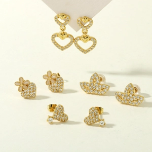 Detailed close-up of golden clover and butterfly earring set with white cubic zirconia