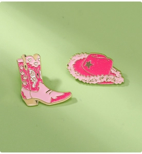 Detail of pink enamel boot and hat brooches with let's go girls text and gold edges