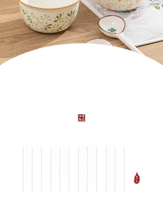 Detail of hand-painted floral ceramic bowl and matching spoon on light wood table