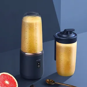 Portable electric blender with extra sports cup and fresh juice on dark blue background