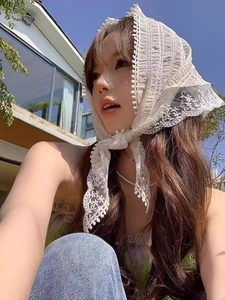 Detail of white lace bandana featuring delicate hollow embroidery and small ball tassels