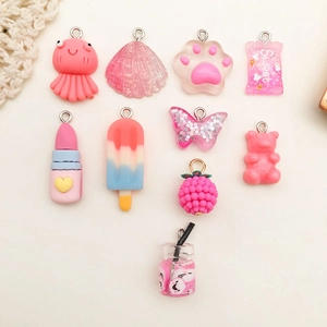 Flat lay of pink resin DIY charms featuring octopus, shell, bear, and lipstick shapes