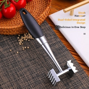 Detail of dual-sided metal steak hammer with ergonomic black handle in kitchen setting
