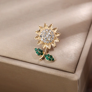 Gros plan d'une broche tournesol dorée avec des cristaux de strass clairs et verts
