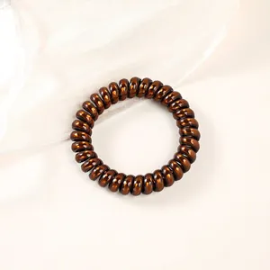 Detail of coffee brown spiral phone cord hair tie with a glossy metallic finish texture