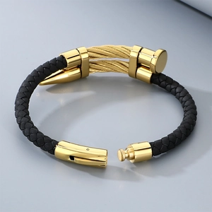 Detailed view of the gold stainless steel nail head on a black braided leather punk bracelet