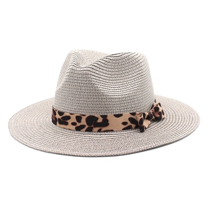 Detail of summer straw fedora hat featuring leopard print ribbon and bow decoration