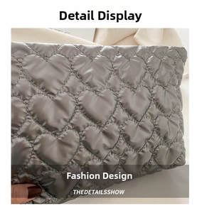 Detailed close-up of grey quilted handbag featuring a heart-shaped stitched pattern