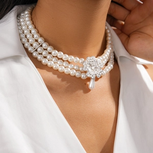 Macro view of a three-row pearl necklace with diamond flower and teardrop pendant