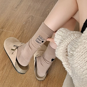 Detail of khaki crew socks with Follow Your Heart embroidery and suede clogs