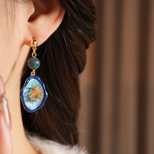Detail view of vintage style floral earrings with green beads and blue petal drop pendants