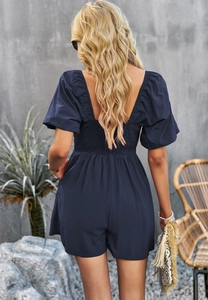 Detail view of navy blue puff sleeve romper showing elastic waist and back design