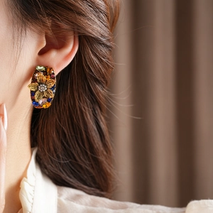 Detailed view of vintage gold earrings featuring multi-color crystals and small pearls